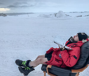 Linc sitting outside in an armchair with Newcomb Bay in background