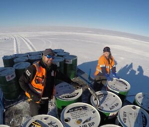 Two expeditioners moving fuel drums