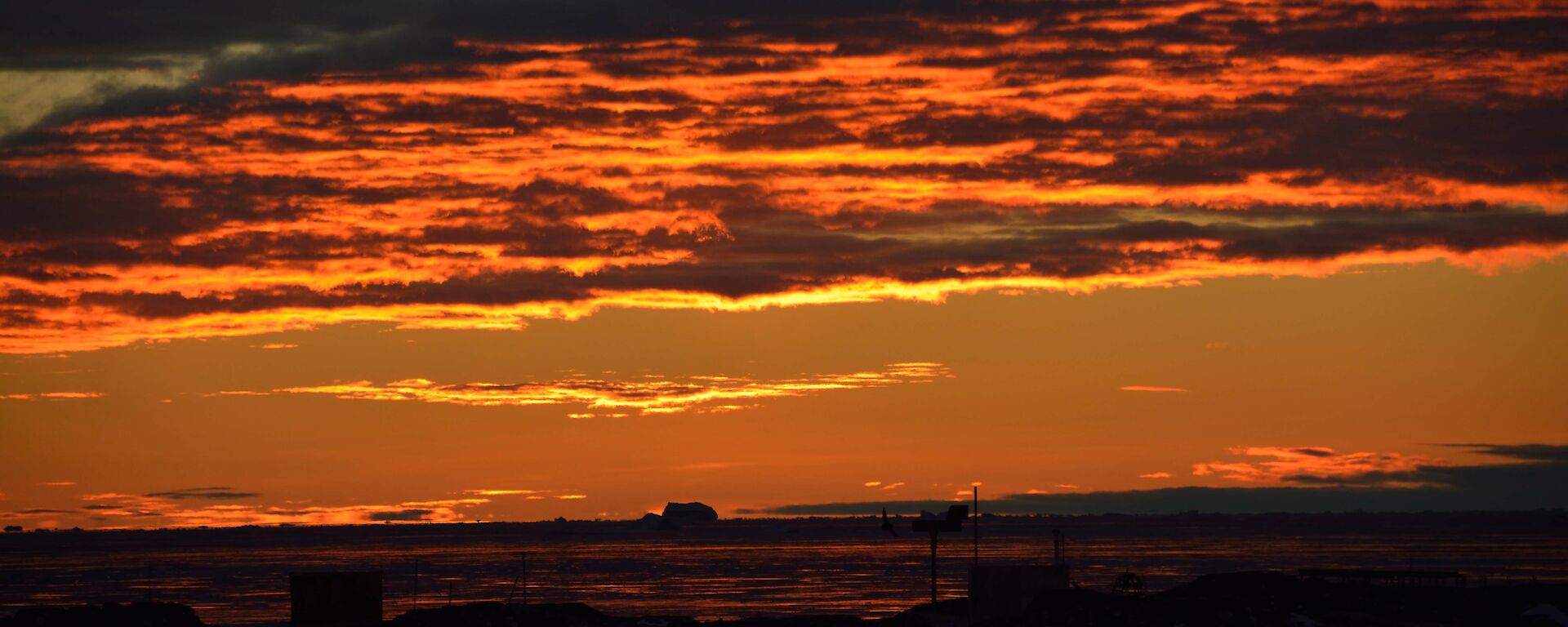 An orange and yellow sunset peeking through the clouds.