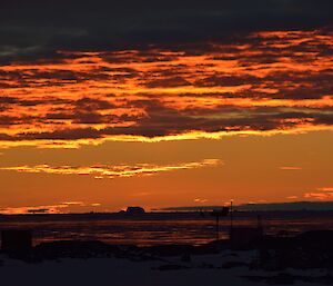 An orange and yellow sunset peeking through the clouds.