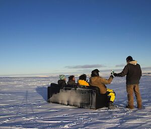 A sofa out on the ice with expeditioners sitting on it outside