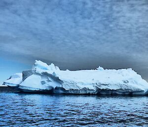 Iceberg with interesting clouds above it.