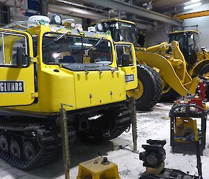 Yellow Hägglunds in the workshop getting repairs.