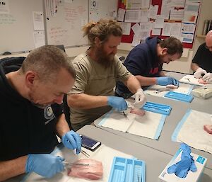 Expeditioners practicing suturing at a table.