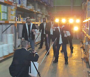 Expeditioners wearing evening suits in the green store filming for the 48 hour Antarctic film festival.