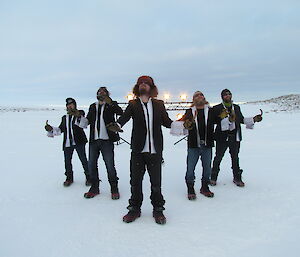 Five expeditioners in suits on the snow during filming of the 48 hour Antarctic film festival.