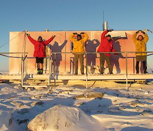 Three expeditioners dancing in front of a building.