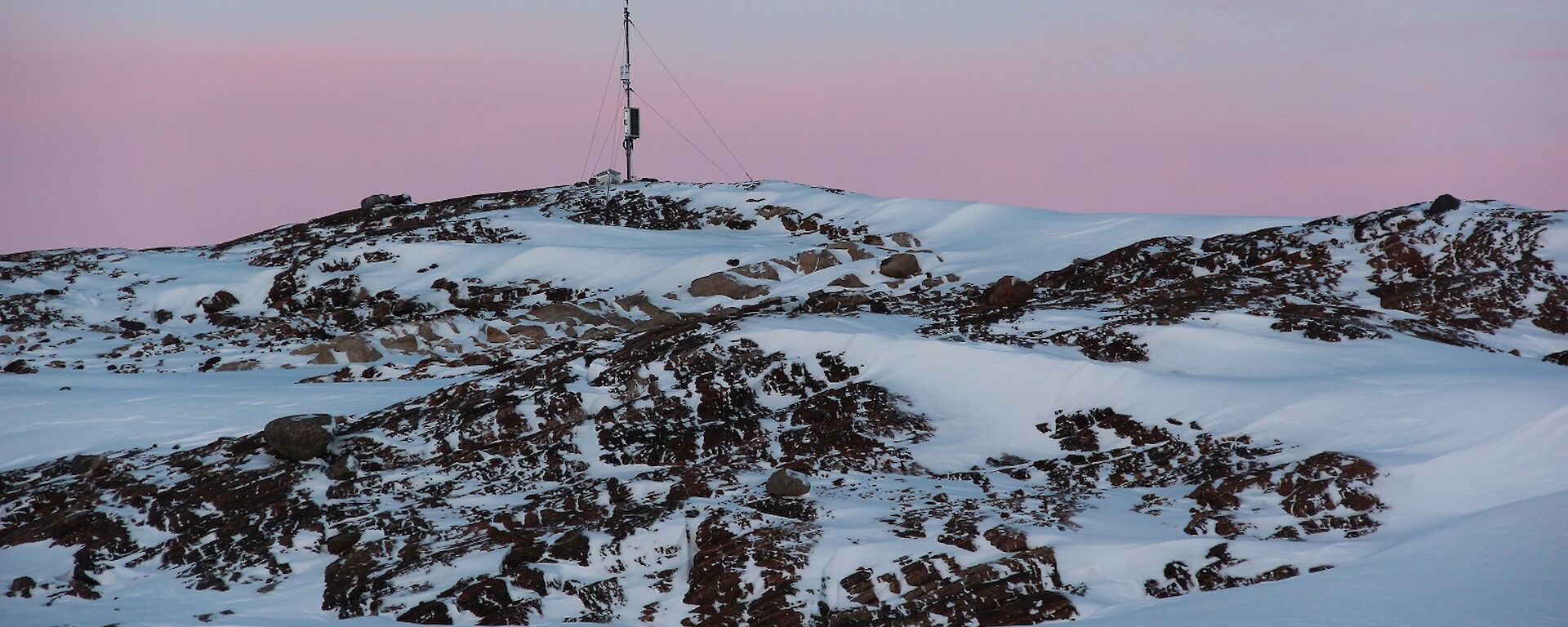 AWS mast on a rocky hill with pink sky