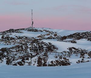 AWS mast on a rocky hill with pink sky