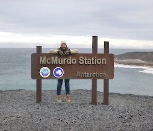 Ducky at McMurdo sign with open water behind him.
