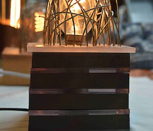 A hand made lamp that has a lot of wires artistically put around the globe.