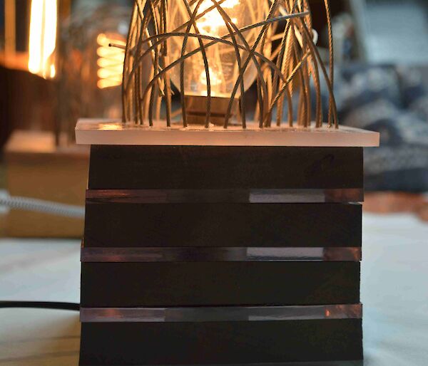 A hand made lamp that has a lot of wires artistically put around the globe.