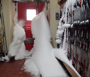 Snow coming through a door in the cold porch.