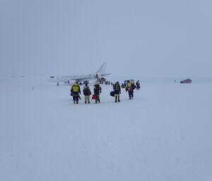 Aircraft with expeditioners standing around outside.