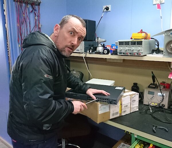 Stu with screw driver working on a bench.