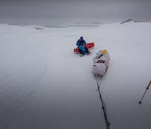 Two sleds and an expeditoner on sea ice.