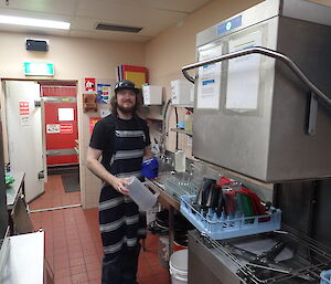 A man in the kitchen cleaning up.