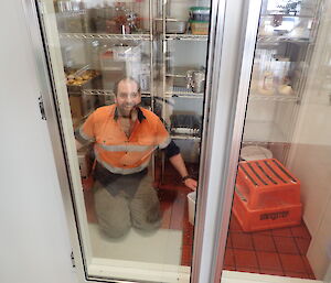 A man cleaning long glass doors on a big refrigerator.