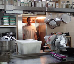 Adam in the kitchen looking at all the pots and pans on a bench.