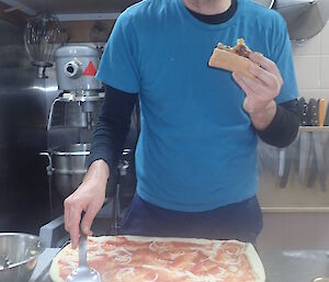 Clint eating some pizza in the kitchen.