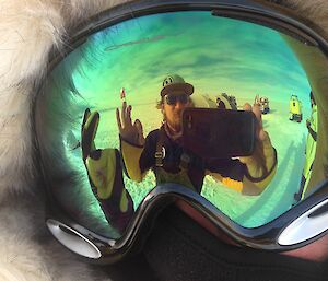 Reflection of Steve in outdoor goggles worn by another expeditioner.