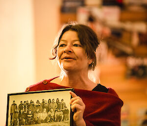 Lady in red jumper holds black and white phote of wintering expeditoners