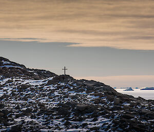 Stoney Hill in foreground with cross and two people silouetted against a sunset
