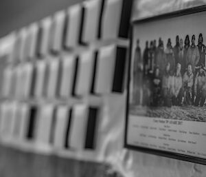 Black and white photo of wintering expeditioners with photos of previous years in background