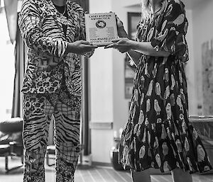 Man in zebra print suit and fur rimmed cowboy hat received plaque from femal station leader