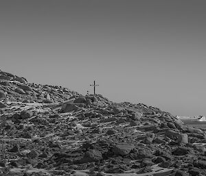 Rocky hill with cross on top with expeditioners sillouetted against the horizen