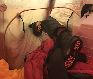 Inside of tent, snow covered tent flap just showing one shoe and leg with shoe protruding through the hole