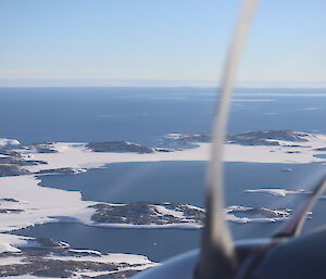 Photo taken out of a plane showing islands and part of a prop of the plane.