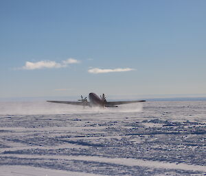 photo of plane taking off on an ice runway with blue sky.