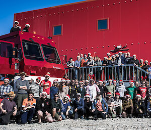 Group of people in front of a red shed with a red bus.