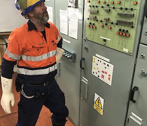 Man wearing high vis shirt looking at a switchboard.