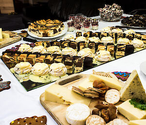 A large table covered in dishes for dessert and cheese platters