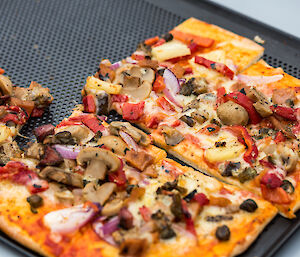 Rectangular tray of vegitarian pizza with half left.