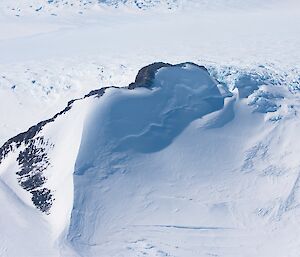 Rocky mountain peak projecting out of ice plateau with glaciated cravases behind and to right hand side