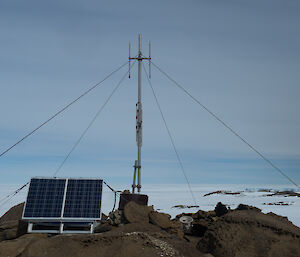 Rocky foreground, antenna in centre with four guide lines running out and solar panel at front left
