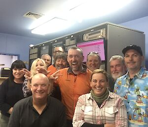 A large group of people in assorted clothing standing in front of a computer rack