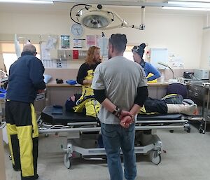 Exam room of the medical centre with patient on bed with four people standing over him