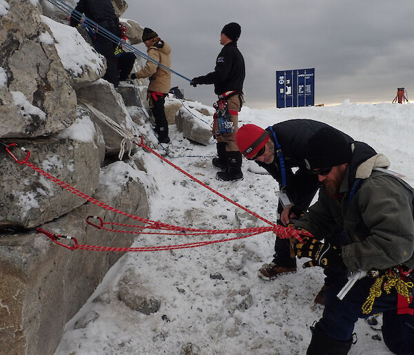 Building rope and carabiner anchoring systems into rock wall.