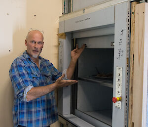 Man opens the sliding doors to a small goods lift