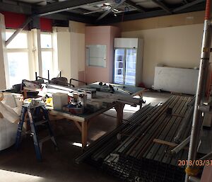 Large room gutted of any fixtures, large work bench in centre and in back left corner a small goods lift with a two door fridge beside