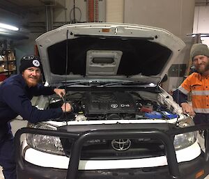 Hilux ute with bonnet open, with man either side servicing the vehicle