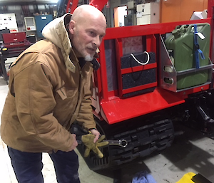 Expeditioner in mechanical workshop standing at door of hagglunds with spanner in hand looking unsure