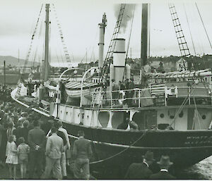 Ship in port with crowd gathered around.