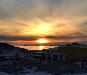 Looking across the station’s weather compound to the sea, with the sun setting in the distance creating a golden glow in the sky and across the water