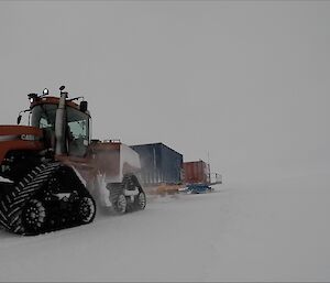 Tractor towing two shipping container of skids