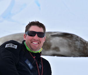 Man posing at front of picture with weddel seal in background